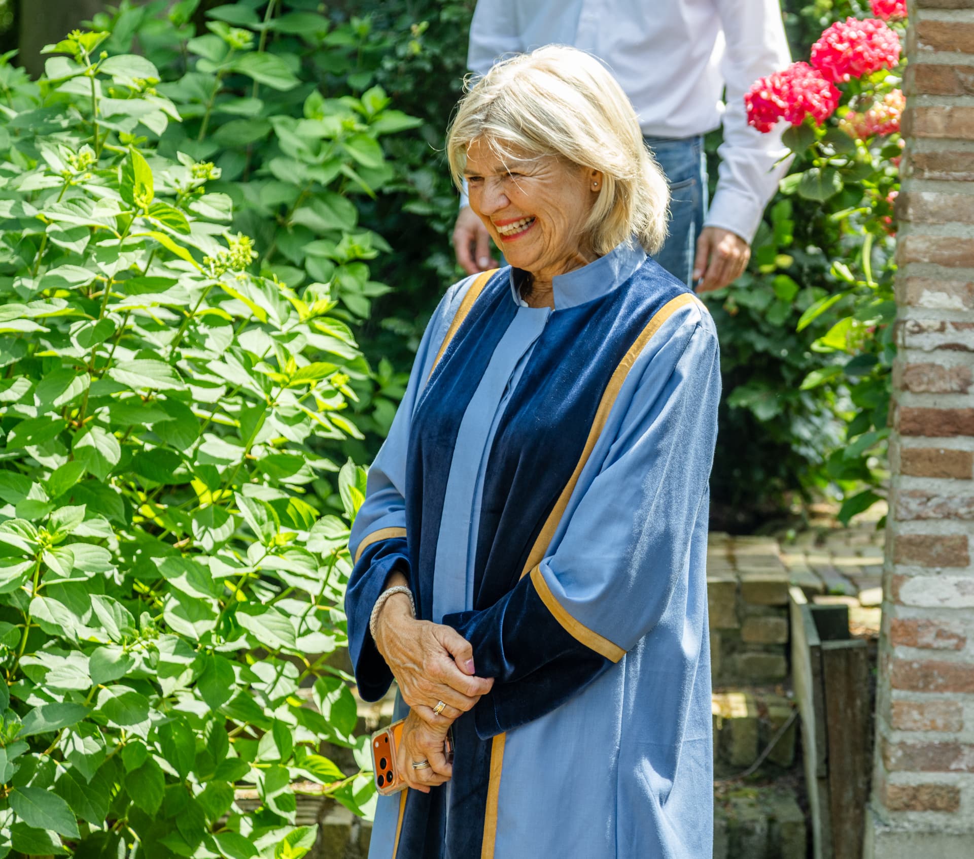 Esther in haar ambtsgewaad in een bloeiende tuin